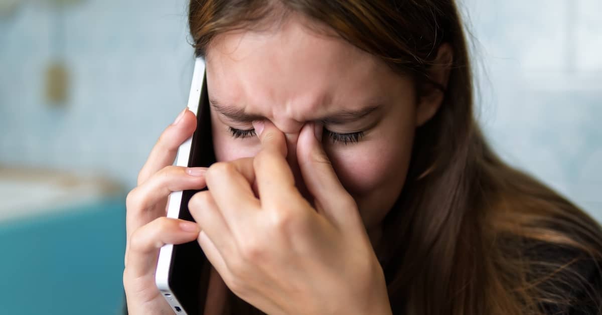 Upset woman on phone with debt collector. | Bernheim Kelley Injury Lawyers