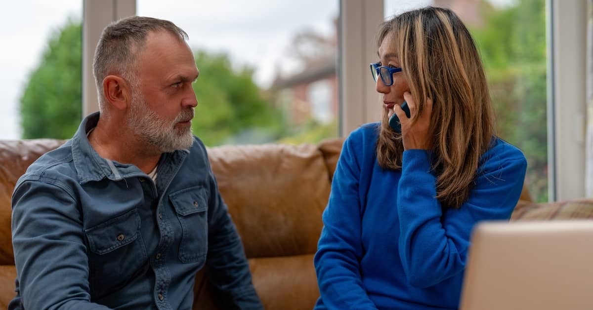 Man sits next to wife on phone with debt collector. | Bernheim Kelley